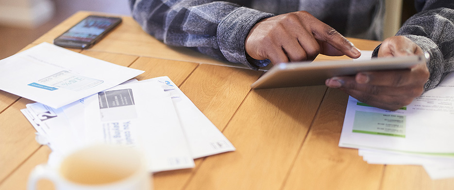 man-on-tablet-at-table-with-bills